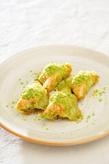 Pistachio baklava on a white wooden background. Baklava on a marble floor. Turkish baklava with pistachio, baklava slice