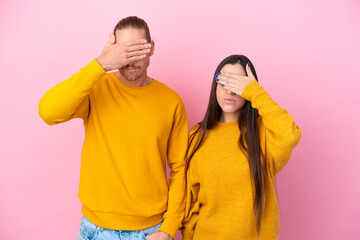 Fototapeta premium Young caucasian couple isolated on pink background covering eyes by hands. Do not want to see something
