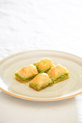 Pistachio baklava on a white wooden background. Baklava on a marble floor. Turkish baklava with pistachio, baklava slice