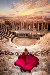 Adventure photo tourist woman in red dress on background Amphitheater in Hierapolis ancient city...