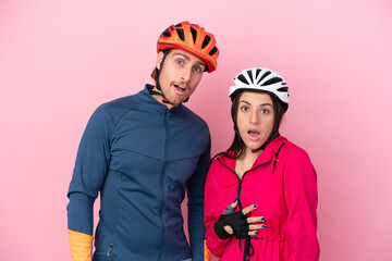 Young cyclist caucasian people isolated on pink background with surprise and shocked facial expression