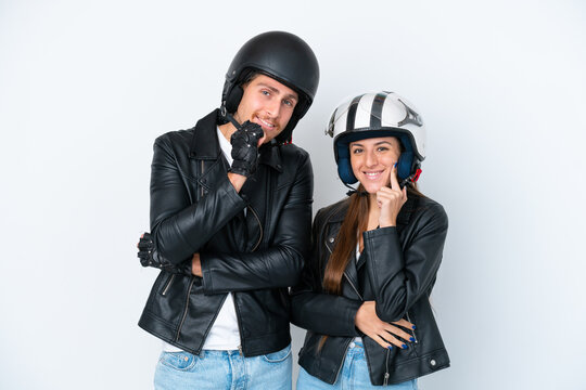 Young caucasian couple with a motorcycle helmet isolated on white background smiling with a sweet expression