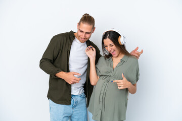 Young caucasian couple isolated on white background pregnant and listening music