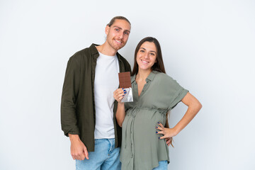 Young caucasian couple isolated on white background pregnant and holding chocolate