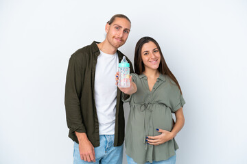Young caucasian couple isolated on white background pregnant and holding a feeding bottle