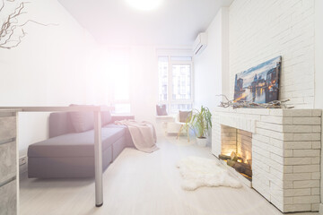 Fototapeta na wymiar fashionable modern design studio apartment with a free layout in a minimal style. very bright huge spacious room with white walls and wooden elements. sitting area with fireplace