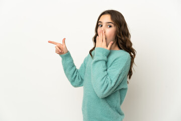 Little caucasian girl isolated on white background with surprise expression while pointing side