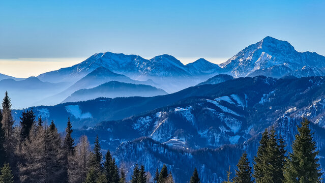 Panoramic view on snow capped mountain peaks of Karawanks in Carinthia, Austria. Julian Alps. Winter wonderland in the Austrian Alps, Europe. Ski tour, snow shoe hiking. Hochobir. Blue misty hills.