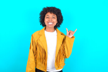 Young woman with afro hairstyle wearing yellow fringe jacket over blue background showing up number six Liu with fingers gesture in sign Chinese language