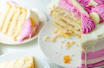 Moist madeira sponge, layered with plum and raspberry jam, coated and topped with white and pink colour frostings, decorated with white chocolate decorations