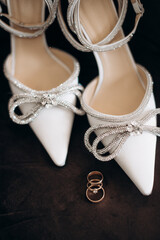 wedding rings with precious stones on the background of the bride's shoes