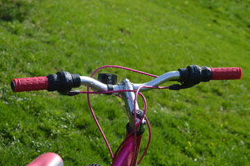 pink mountain bike handle bars with brakes, gear shifts and a light