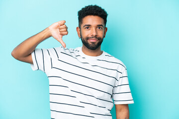 Young Brazilian man isolated on blue background showing thumb down with negative expression
