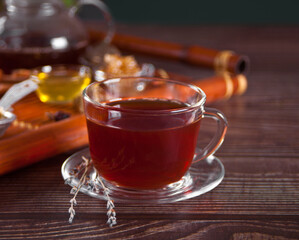 Cup of herbal tea with flowers, honey in jar, teapot and and various dried herbs on the tray.