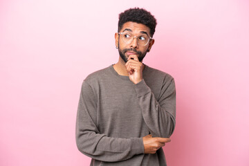 Young Brazilian man isolated on pink background having doubts and thinking