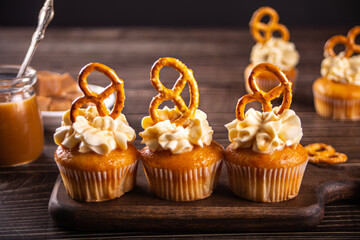 Homemade cupcakes with caramel syrup with whipped cream cheese and brezel waffles decoration