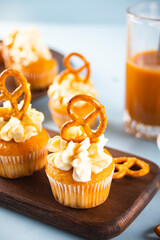 Homemade cupcakes with caramel syrup with whipped cream cheese and brezel waffles decoration