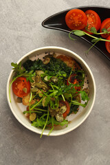 Vegetarian salad with potato, tomatoes, arugula and 
pumpkin seeds in round paper take-away container on gray background. Healthy food delivery concept. Free space for text.