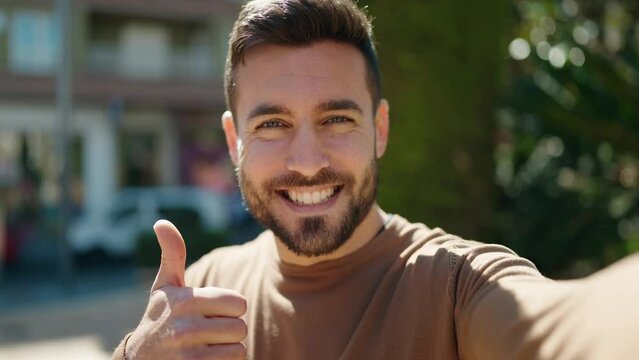 Young hispanic man smiling confident making selfie by camera at street