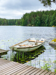 Old rowing boat tied to jetty on forest lake © FoxglovesAndStocking