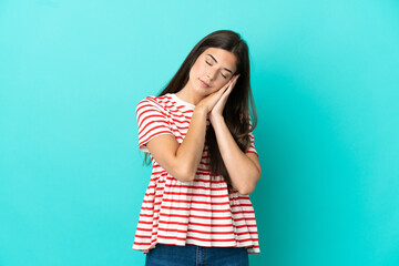 Young Brazilian woman isolated on blue background making sleep gesture in dorable expression