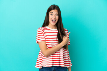 Young Brazilian woman isolated on blue background surprised and pointing side
