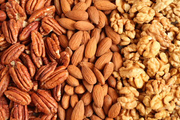 Raw peeled pecans, almonds and walnuts on a linen cloth. Closeup. Macro