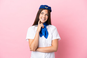 Airplane stewardess Brazilian woman isolated on pink background thinking an idea while looking up