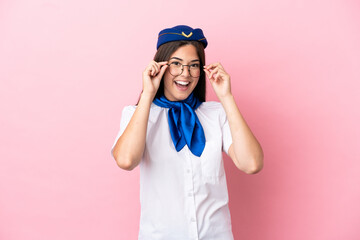 Airplane stewardess Brazilian woman isolated on pink background with glasses and surprised