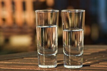 Two glasses with fresh still water outdoors in the summer evening.    