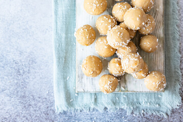 Traditional Indian festival sweets with coconut flakes on wooden board, light background. Laddoo or Laddu, Popular sweet snack in India. Vegan sweets.