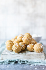 Traditional Indian festival sweets with coconut flakes on wooden board, light background. Laddoo or Laddu, Popular sweet snack in India. Vegan sweets.