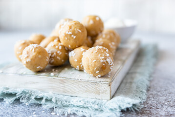 Traditional Indian festival sweets with coconut flakes on wooden board, light background. Laddoo or Laddu, Popular sweet snack in India. Vegan sweets.