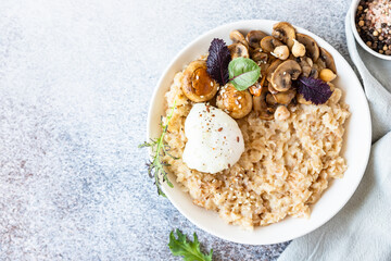 Savory porridge for breakfast. Oatmeal or spelt flakes with poached egg, fried mushrooms and herbs. Healthy food. Keto diet. Top view.