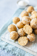 Traditional Indian festival sweets with coconut flakes on wooden board, light background. Laddoo or Laddu, Popular sweet snack in India. Vegan sweets.