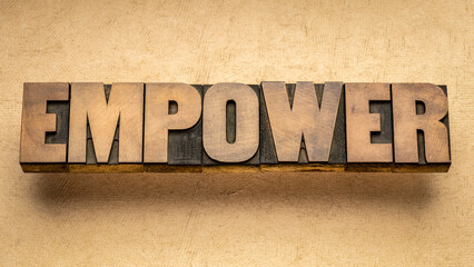 empower word in vintage letterpress wood type against handmade paper, empowerment and leadership...