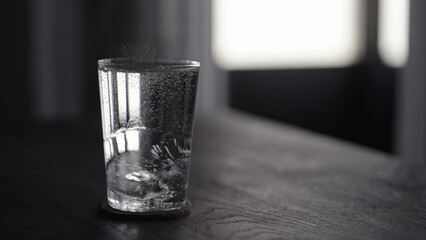 Slow motion pour tonic water over ice ball in tumbler glass on wood table - Powered by Adobe