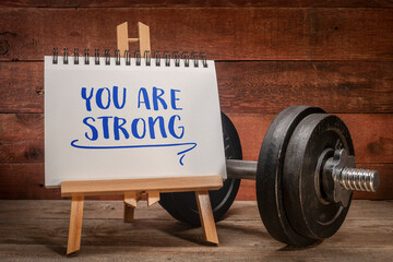 you are strong positive affirmation, a small easel sign with a heavy dumbbell, fitness and personal...