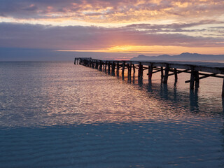 Fototapeta premium Wooden pier in the Mediterranean in Playa de Muro at sunrise. Majorca, Spain