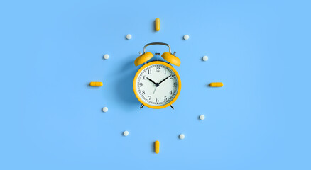Alarm Clock with pills, medical capsules on blue background
