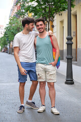 Two young men laughing hugging and looking at camera in the street. Gay couple.