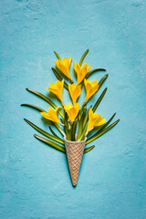 Yellow flowers in ice cream cone on a turquoise textured background