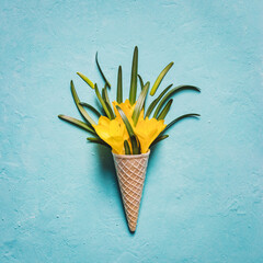 Ice cream cone with yellow flowers on a turquoise textured background