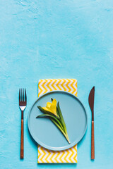 Spring table setting with yellow flower in a plate