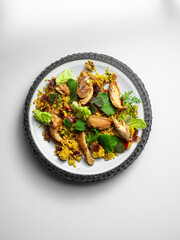 Chicken - Couscous salad,  Datel, herbs, raisins  on a ceramic plate, with a white background.