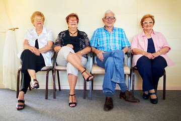Waiting for our grandchildren. Shot of a group cheerful elderly people smiling and posing for the camera inside of a building.