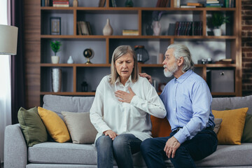 Senior couple at home, woman has severe chest pain and shortness of breath, husband tries to calm wife