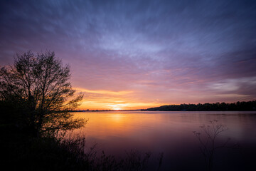 Fototapeta na wymiar Beautiful sunset, sky with clouds above lake with trees around.