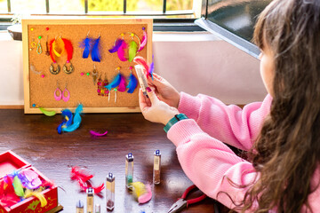 Freelancer woman making earrings in craft studio to sell on internet.
