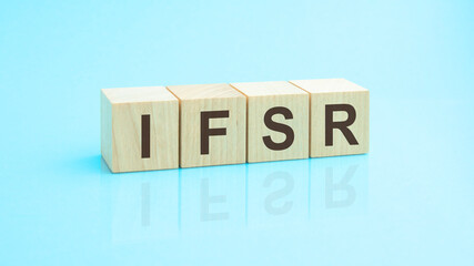 four wooden cubes with the letters IFSR on the bright surface of a blue table